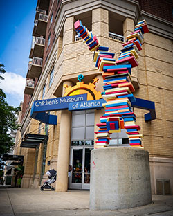 Sculpture of a human figure made from colorful stacked books outside the Children's Museum of Atlanta.