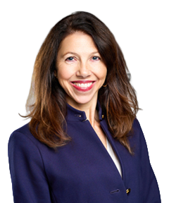 Smiling woman with shoulder-length brown hair wearing a navy blazer against a light gray background.